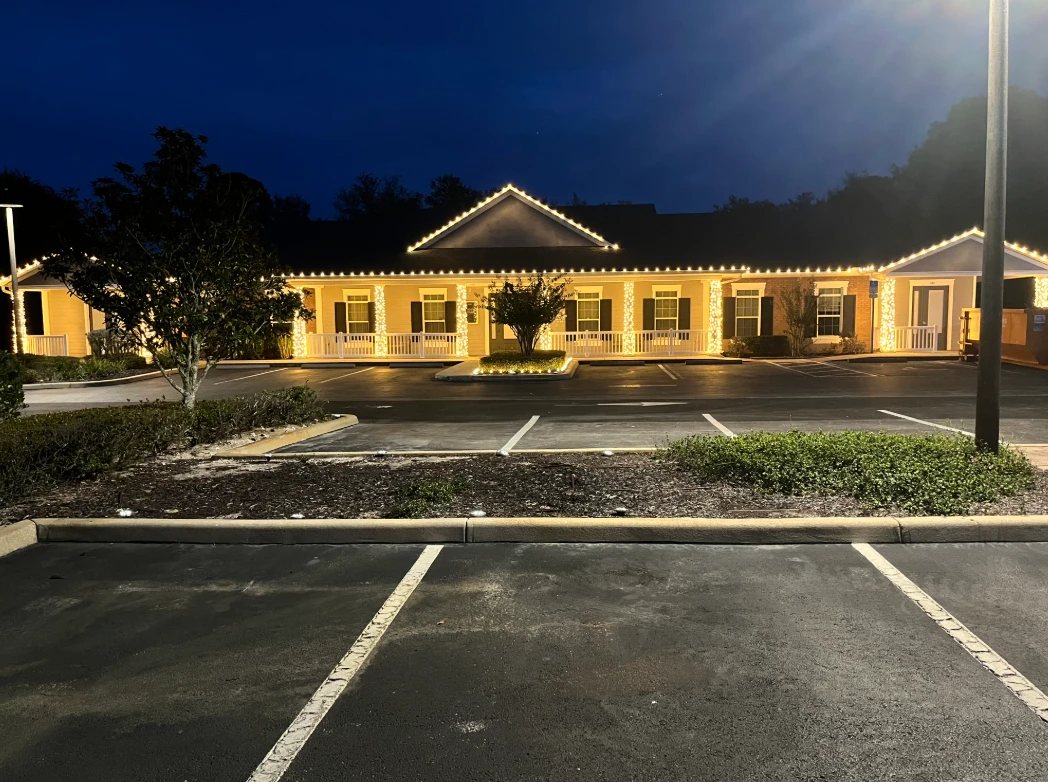 Commercial building with warm white roofline Christmas lights and wrapped porch columns