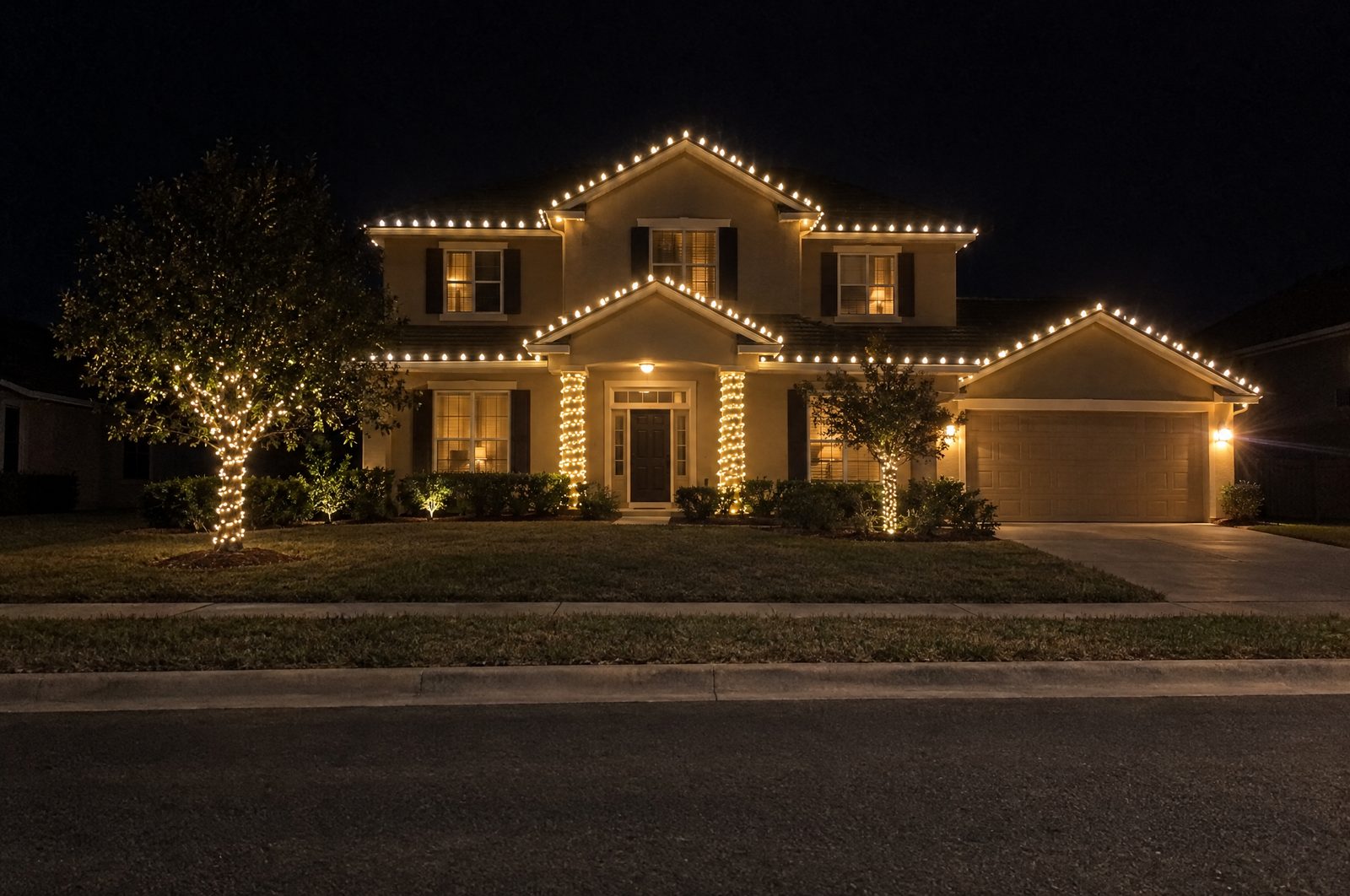 Two-story home at night outlined in C9 bulbs on every roofline and gable with wrapped entry columns